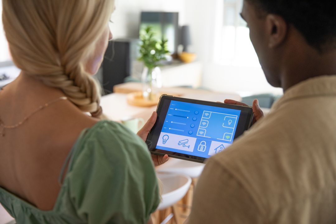 Diverse Couple Controlling Smart Home Using Tablet in Bright Kitchen