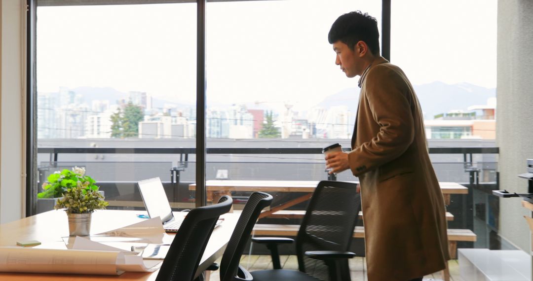 Businessperson Holding Coffee Cup in Modern Office with City View - Free Images, Stock Photos and Pictures on Pikwizard.com