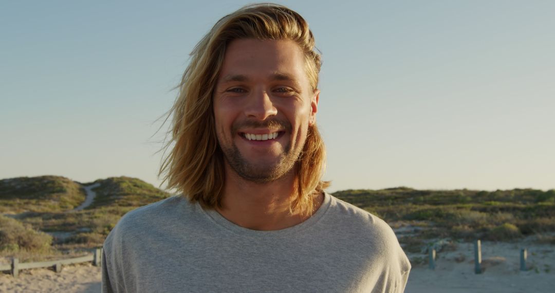 Portrait of happy caucasian man with long blond hair at sunny beach - Free Images, Stock Photos and Pictures on Pikwizard.com