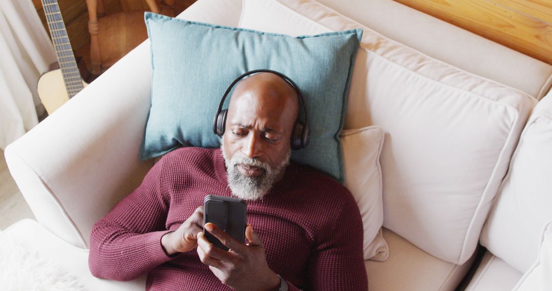 Elderly Man Relaxing on Couch Listening to Music on Smartphone - Free Images, Stock Photos and Pictures on Pikwizard.com