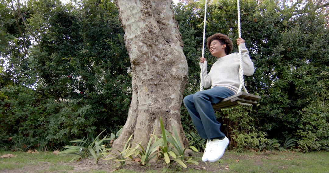 Young Boy Joyfully Playing on Tree Swing in Garden