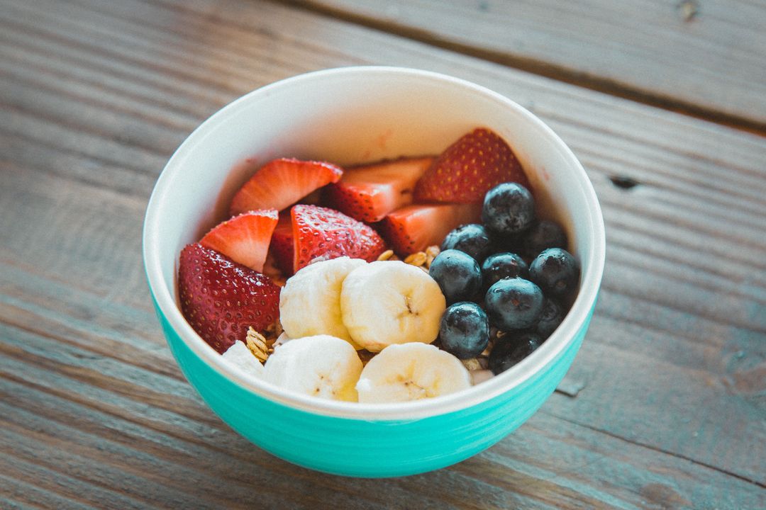 Colorful Breakfast Bowl with Sliced Banana, Fresh Strawberries, Blueberries and Granola