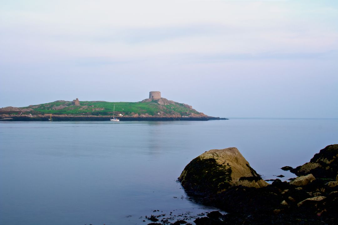 Tranquil Coastal Landscape with Rocky Foreground and Island Tower - Free Images, Stock Photos and Pictures on Pikwizard.com