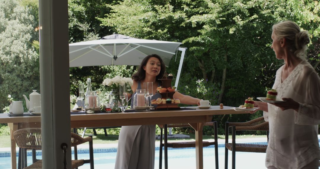 Women Preparing Elegant Poolside Gathering with Desserts and Drinks