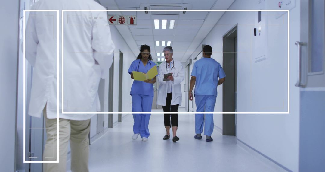 Medical team walking hospital corridor reviewing clinical records and using tablet