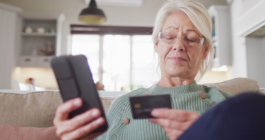 Senior Woman Holding Credit Card While Using Mobile Phone at Home - Free Images, Stock Photos and Pictures on Pikwizard.com