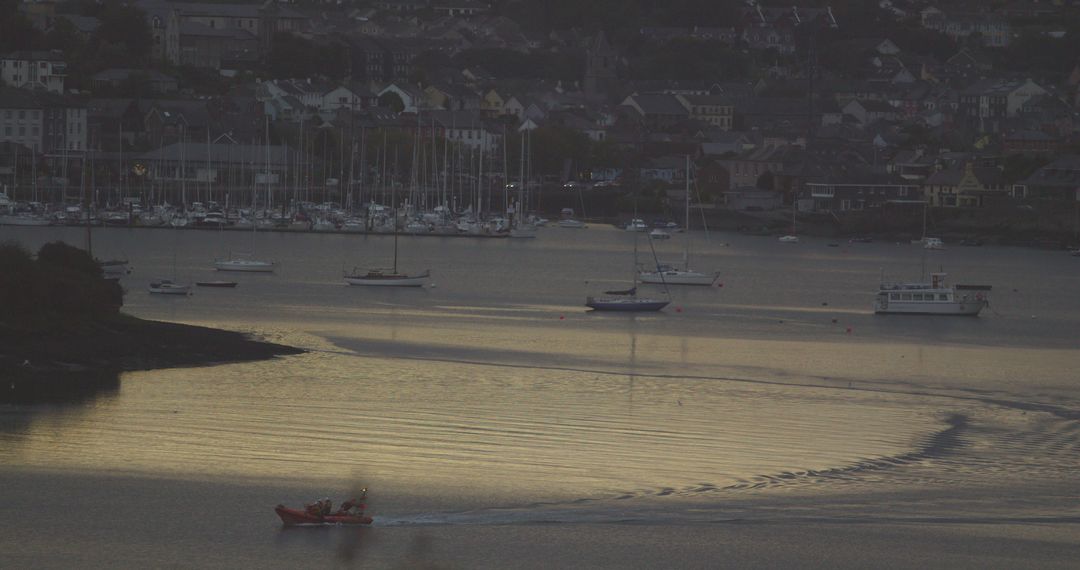 Boat crossing tranquil harbor at dusk with town in background - Free Images, Stock Photos and Pictures on Pikwizard.com