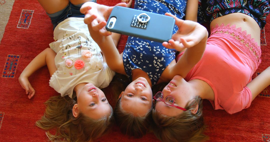 Three Young Girls Lying on Carpet Taking Selfie Together - Free Images, Stock Photos and Pictures on Pikwizard.com