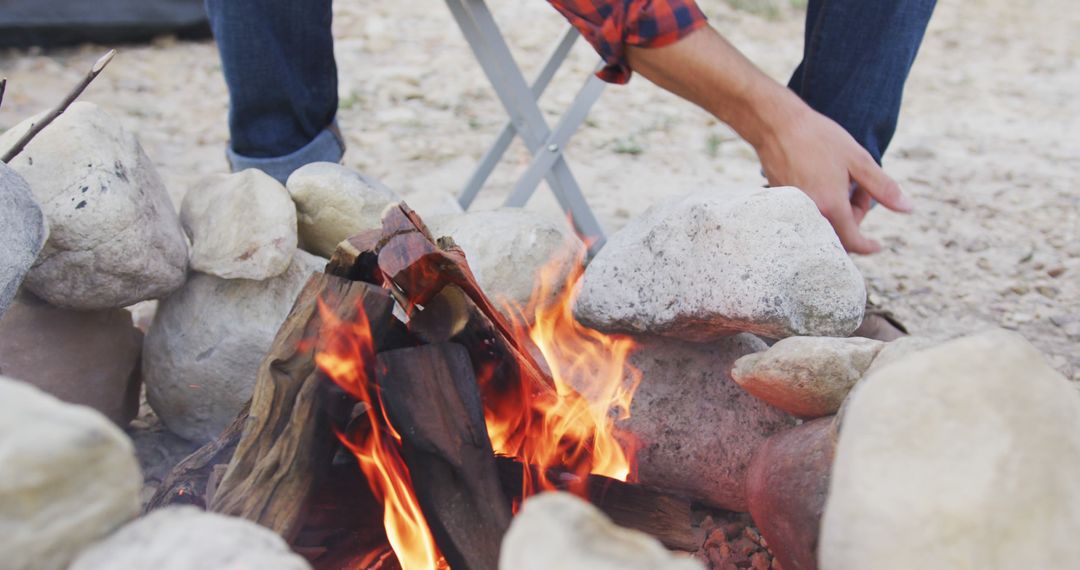 Hands Adding Wood to Outdoor Campfire for Evening Gathering from Pikwizard