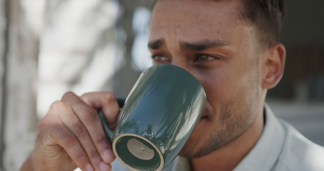 Young Man Drinking Coffee in Sunlit Outdoor Setting - Free Images, Stock Photos and Pictures on Pikwizard.com