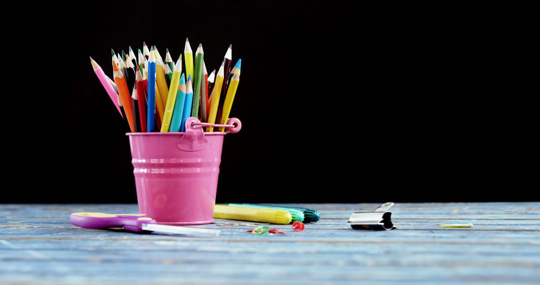 A pink bucket filled with colorful pencils is placed on a wooden surface, with copy space - Free Images, Stock Photos and Pictures on Pikwizard.com