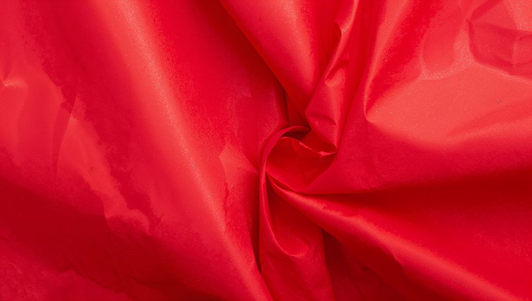 Glossy Red Satin Fabric Twisting into Rosette Knot Close-Up Texture Background