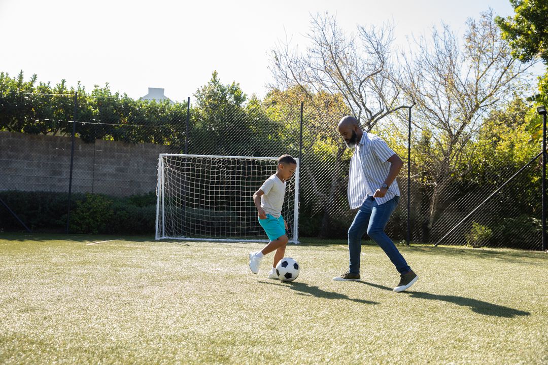 Father and Son Playing Soccer in Backyard with Goal Net