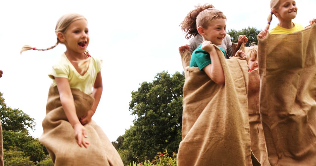 Joyful Children Engaging in Outdoor Sack Race on Sunny Day - Free Images, Stock Photos and Pictures on Pikwizard.com