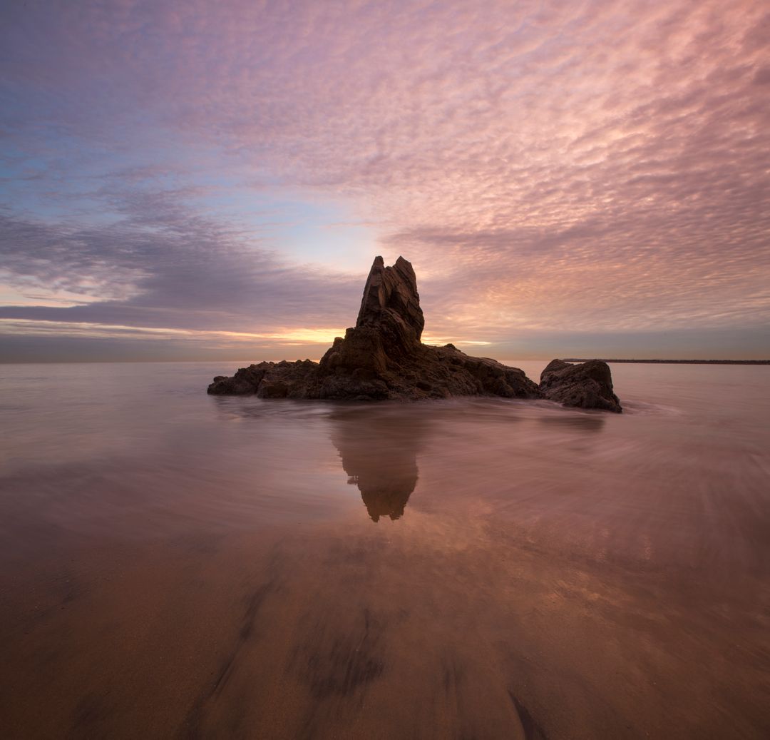 Tranquil Sunset Over Rock Formation on Calm Beach - Free Images, Stock Photos and Pictures on Pikwizard.com