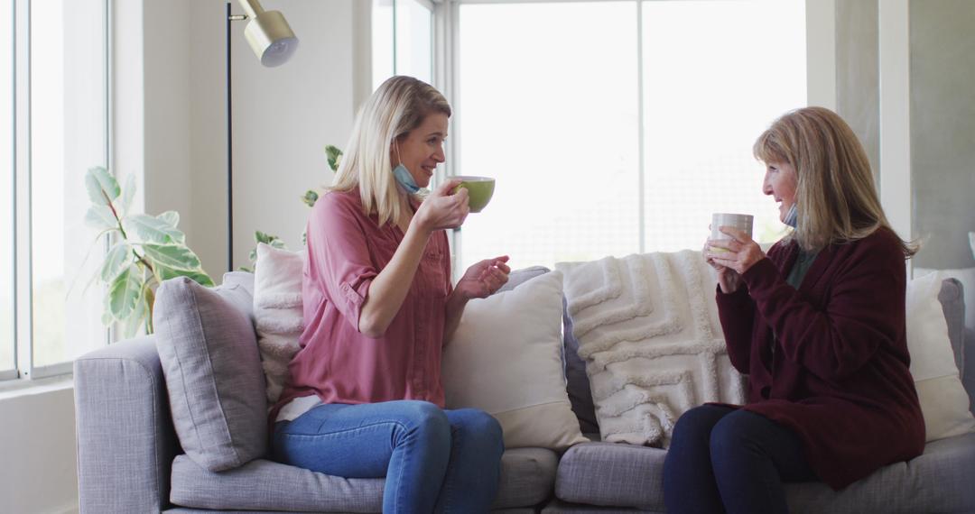 Two Women Sitting on Couch Enjoying Coffee at Home - Free Images, Stock Photos and Pictures on Pikwizard.com