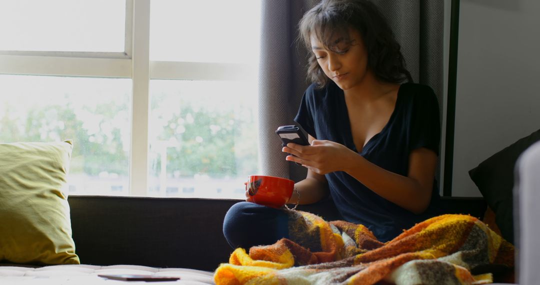 Young Woman Relaxing with Smartphone and Coffee at Home - Free Images, Stock Photos and Pictures on Pikwizard.com