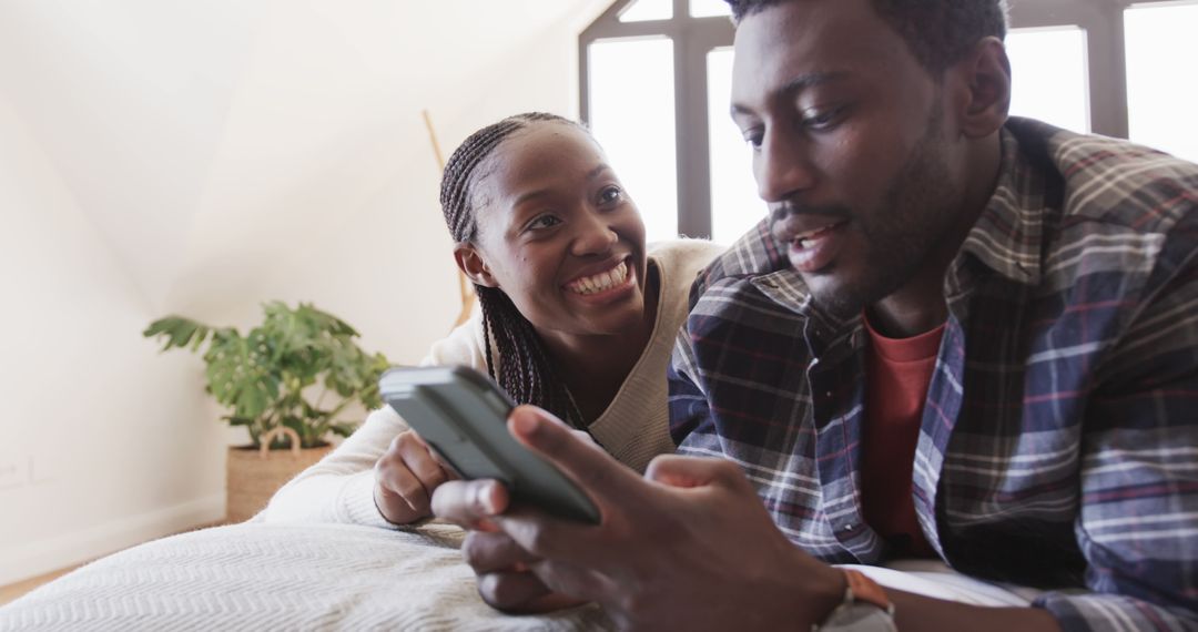 Happy Couple Relaxing at Home Using Smartphone on Bed