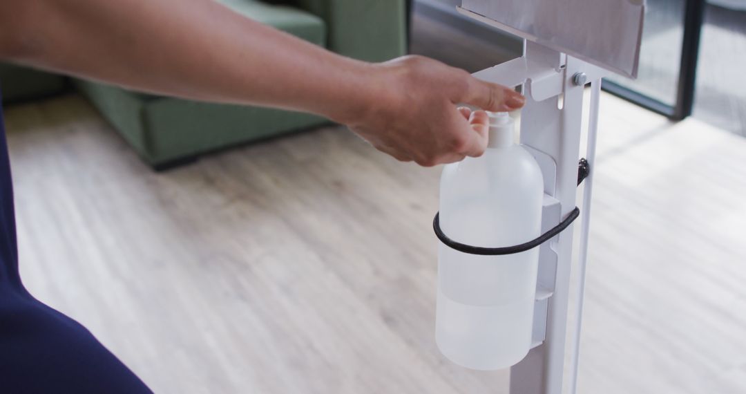 Person using hands-free hand sanitizer dispenser indoors - Free Images, Stock Photos and Pictures on Pikwizard.com