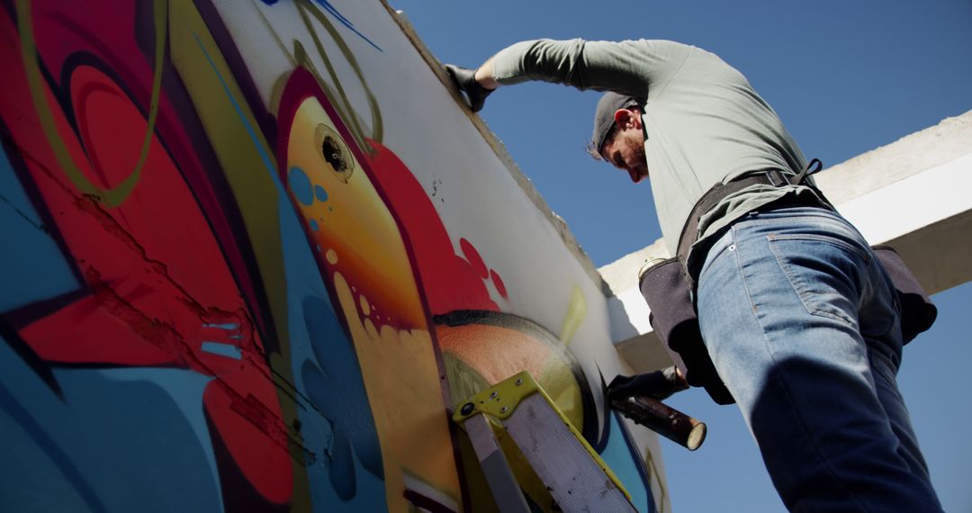 Street artist painting vibrant mural outdoors on sunny day - Free Images, Stock Photos and Pictures on Pikwizard.com