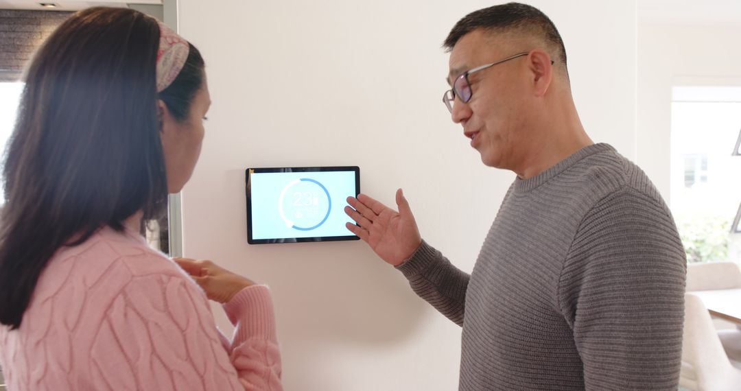 Father and Daughter Adjusting Smart Thermostat at Home