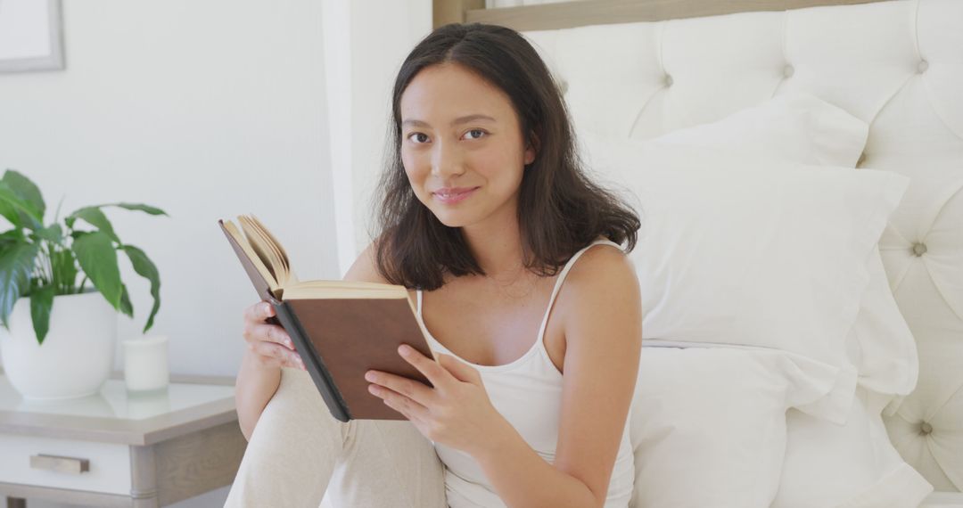 Young Woman Reading Book on Bed in Bright Bedroom - Free Images, Stock Photos and Pictures on Pikwizard.com