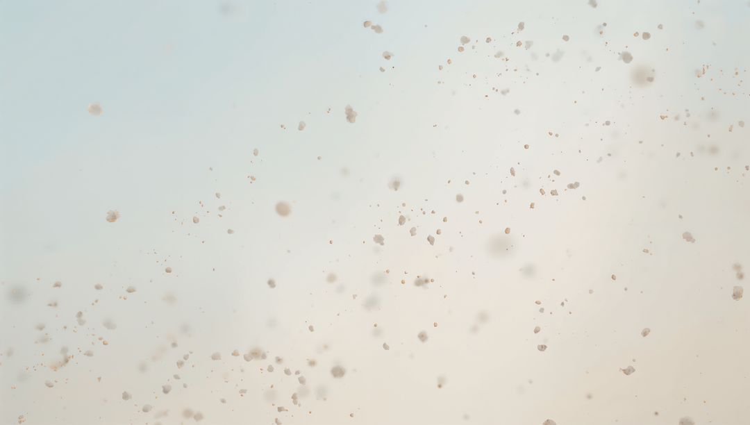 Delicate splattered droplets on translucent glass with pale blue to beige gradient bokeh