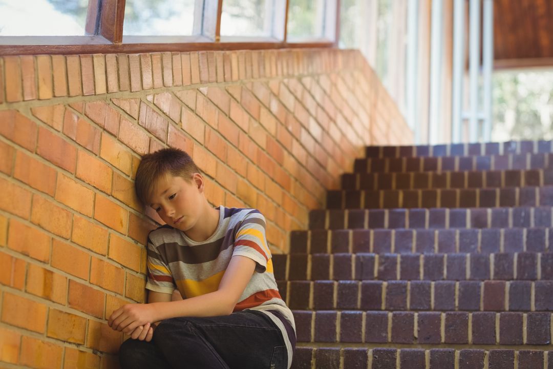 Contemplative Preteen Boy Sitting on Staircase by Window