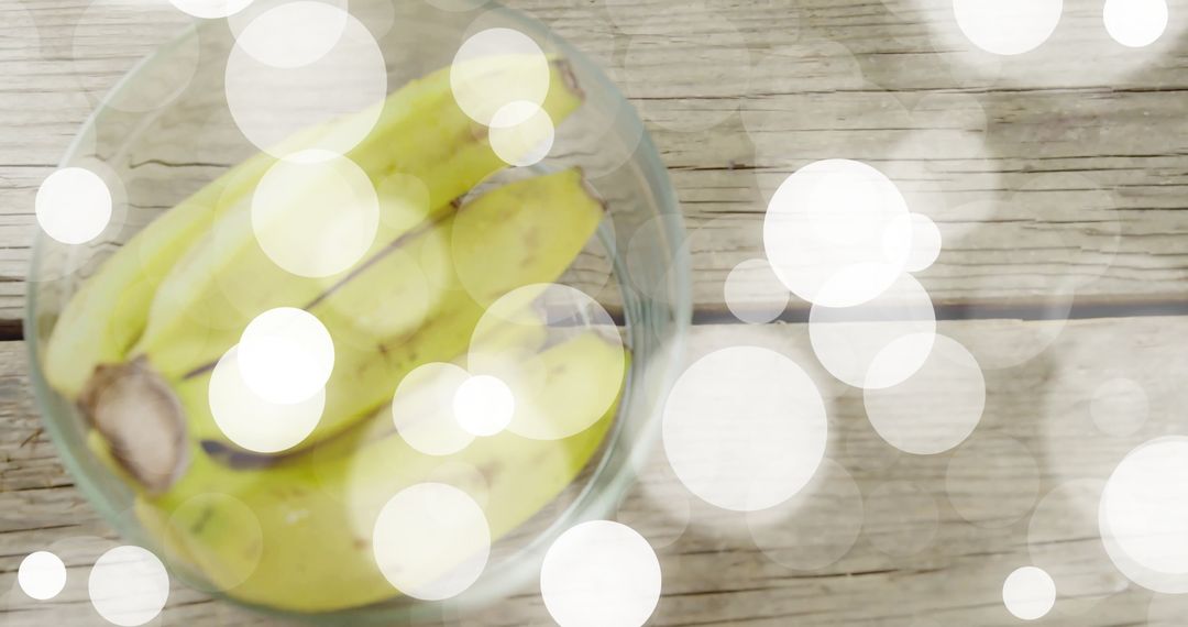 Bananas in Glass Bowl with Bokeh Lights on Rustic Wooden Table