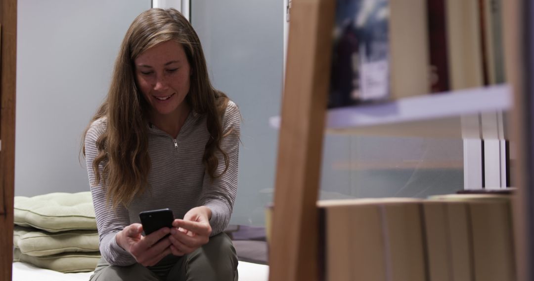 Woman Smiling While Texting on Smartphone in Cozy Home - Free Images, Stock Photos and Pictures on Pikwizard.com