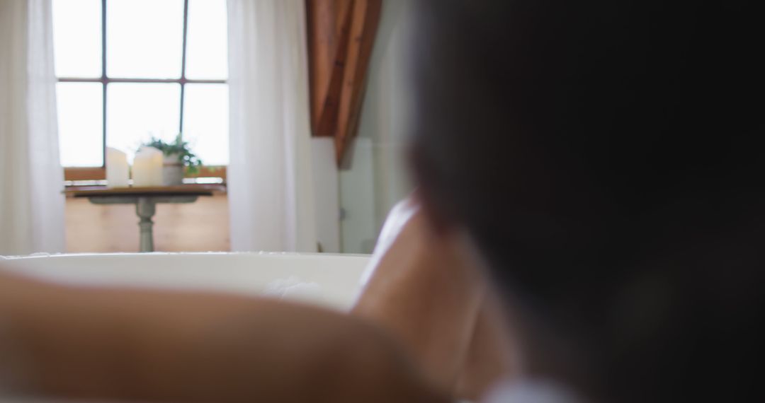 Person Relaxing in Bathtub Facing Window with Natural Light - Free Images, Stock Photos and Pictures on Pikwizard.com