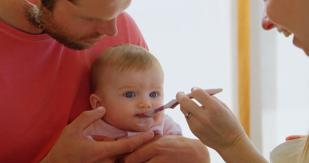 Parents Feeding Happy Baby with Spoon at Home - Free Images, Stock Photos and Pictures on Pikwizard.com