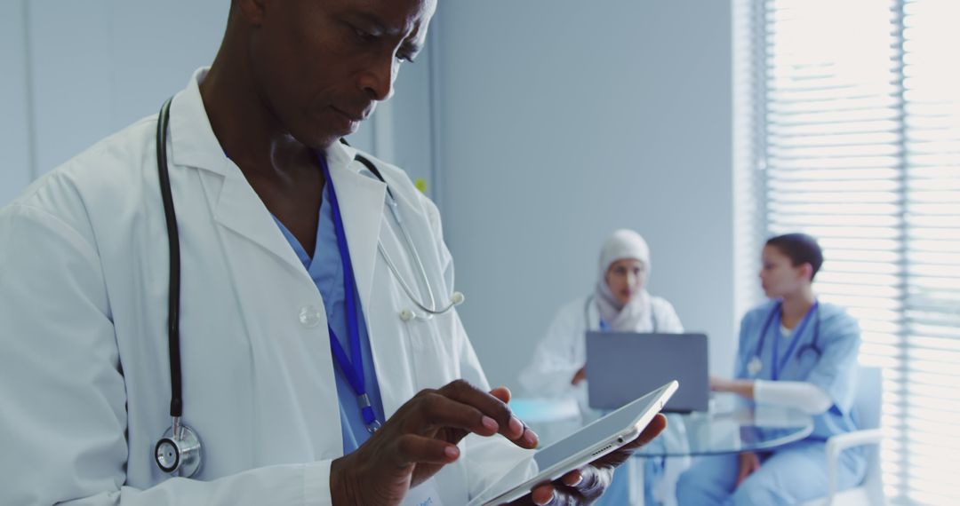 Healthcare Professional Using Tablet with Medical Team Collaborating in Background - Free Images, Stock Photos and Pictures on Pikwizard.com