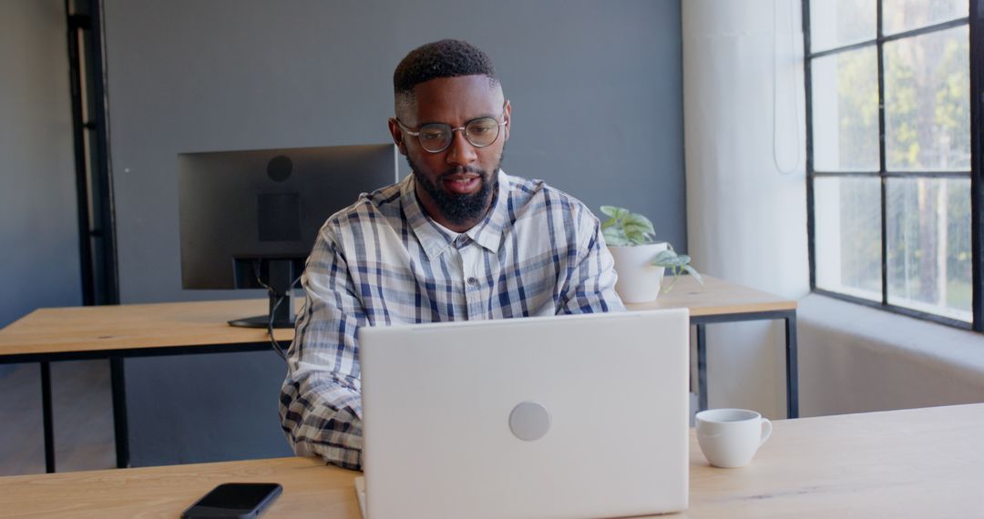 Focused Young Man Efficiently Working on Laptop in Modern Office