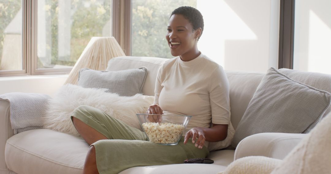 Smiling Woman Relaxing on Sofa Eating Popcorn in Cozy Living Room - Free Images, Stock Photos and Pictures on Pikwizard.com