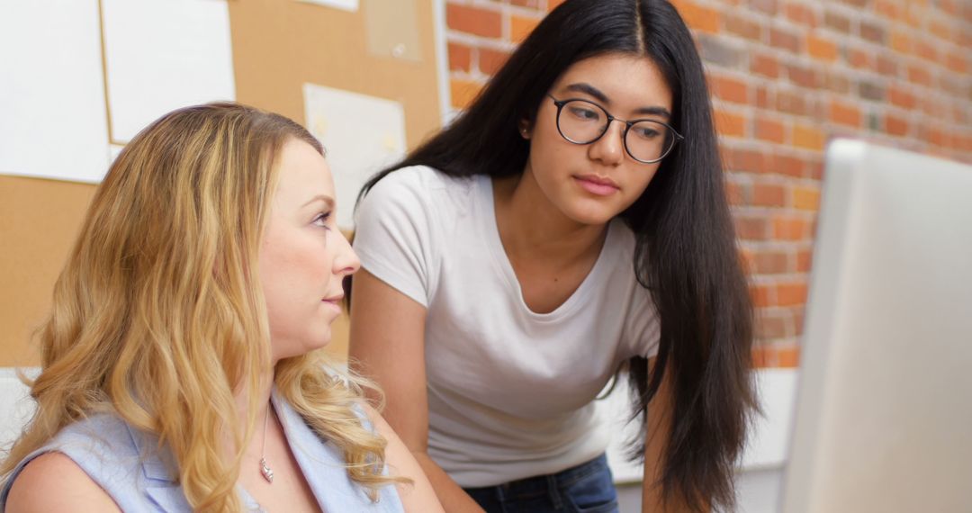 Two Women Collaborating on Office Project at Computer