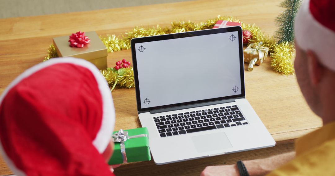 Couple in Santa Hats Sharing Christmas Gift Near Laptop - Free Images, Stock Photos and Pictures on Pikwizard.com