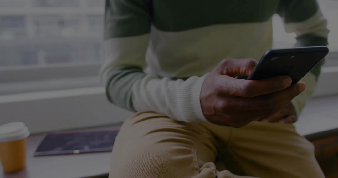 Man Relaxing on Window Ledge Checking Smartphone