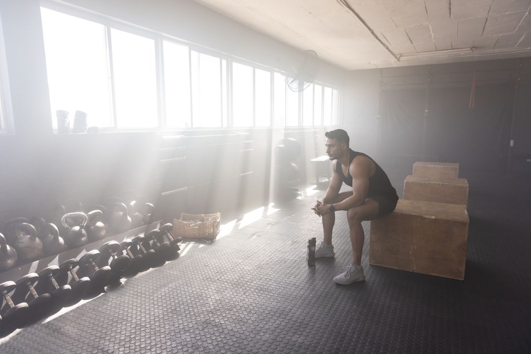 Athlete Resting in Gym with Kettlebells and Sunlight
