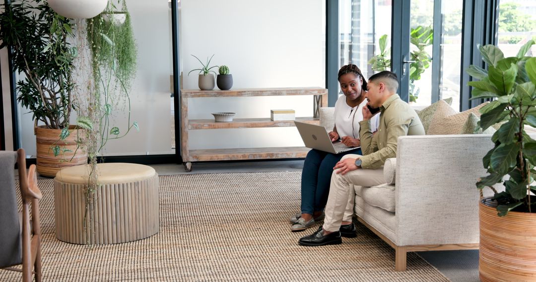 Colleagues Collaborating in Modern Office Lounge Area with Laptop