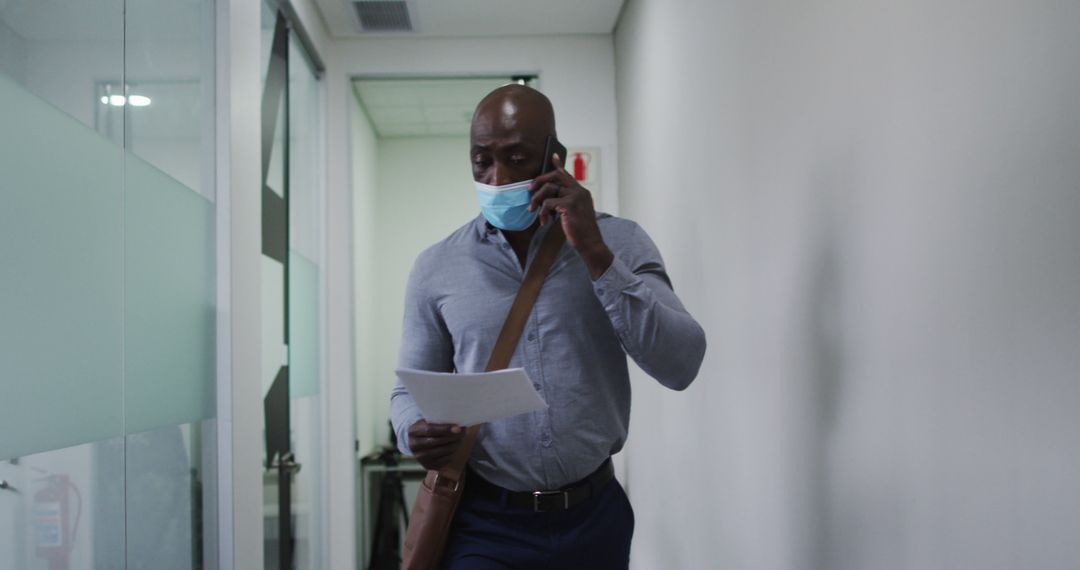 Professional Man Walking in Office Hallway Wearing Face Mask - Free Images, Stock Photos and Pictures on Pikwizard.com