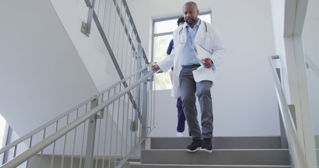 African american male and female doctors walking stairs at hospital - Free Images, Stock Photos and Pictures on Pikwizard.com