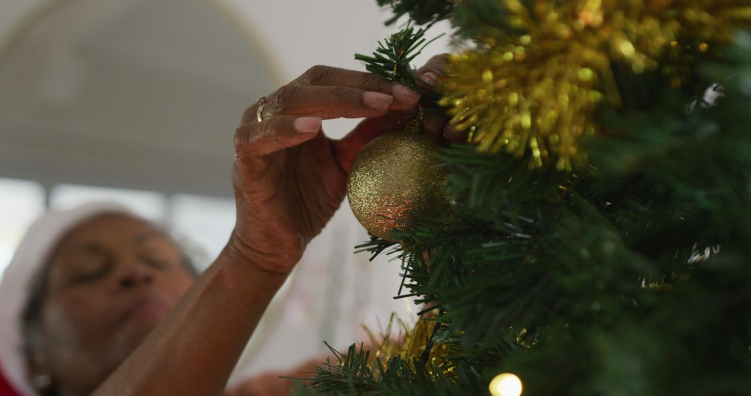 Senior Woman Decorating Christmas Tree with Golden Ornament - Free Images, Stock Photos and Pictures on Pikwizard.com