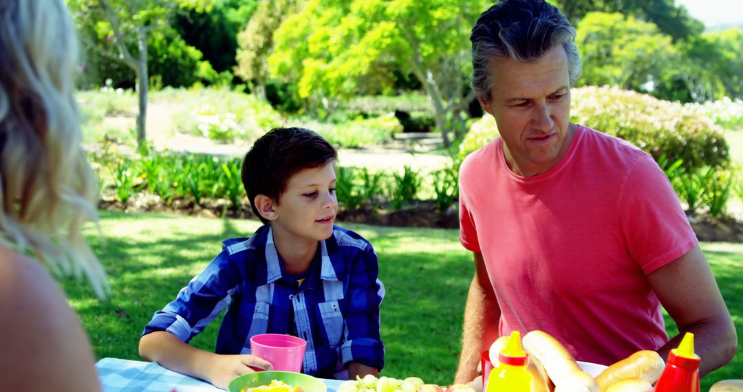 Father and Son Enjoying Outdoor Picnic in Park on a Sunny Day - Free Images, Stock Photos and Pictures on Pikwizard.com