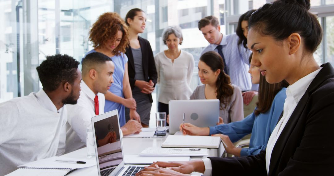 Diverse Team in Corporate Meeting Analyzing Data on Laptops