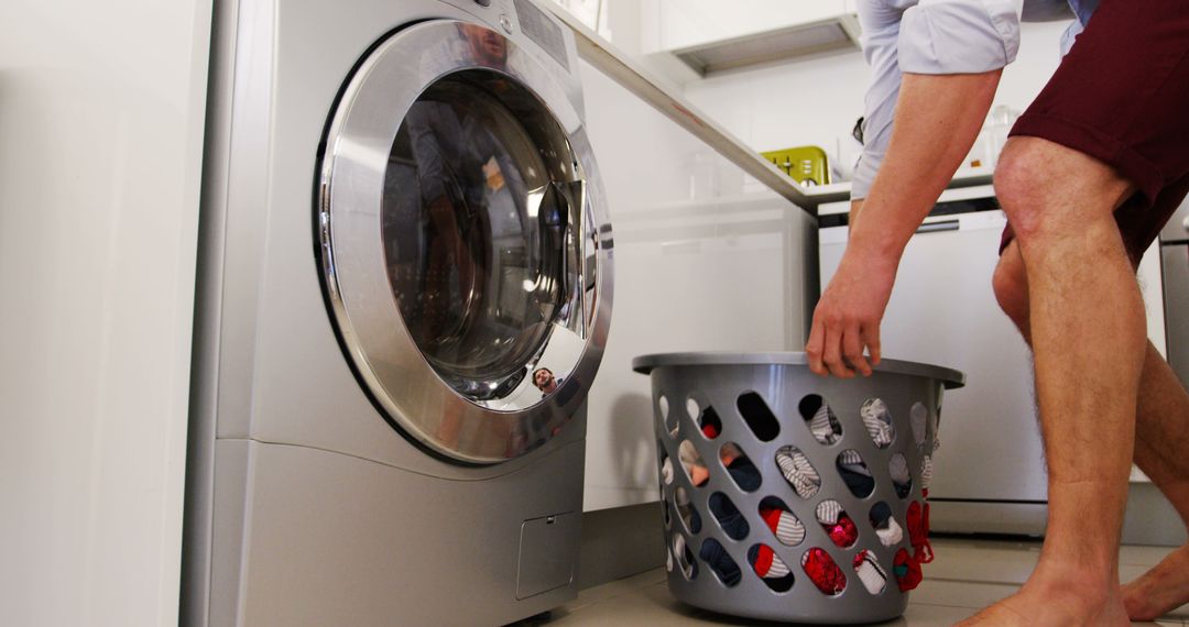 Caucasian Man Doing Laundry Using a Washing Machine in Bright Kitchen - Free Images, Stock Photos and Pictures on Pikwizard.com