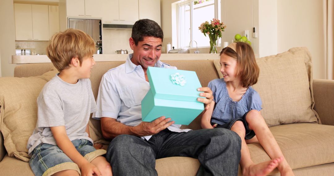 Father with Children Excitedly Opening Gift Box in Living Room - Free Images, Stock Photos and Pictures on Pikwizard.com