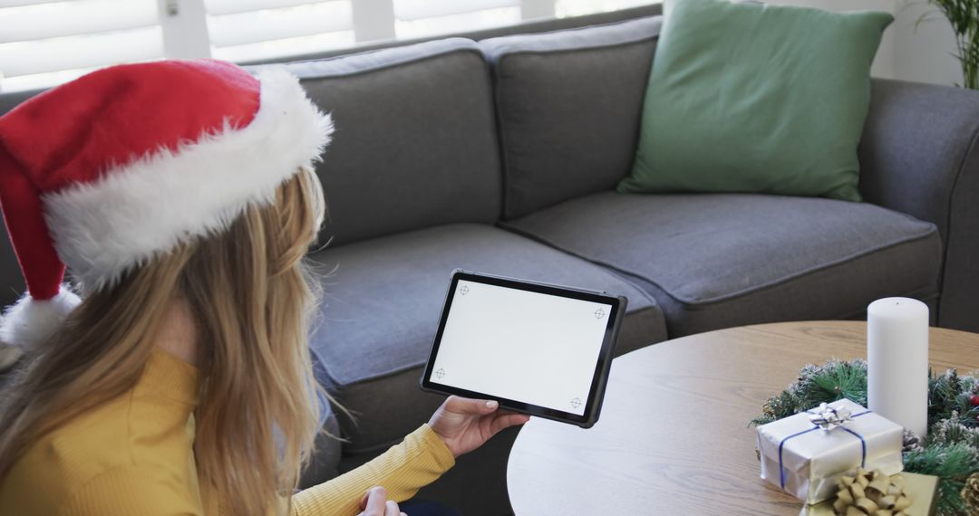 Woman Wearing Santa Hat Holding Tablet at Christmas - Free Images, Stock Photos and Pictures on Pikwizard.com