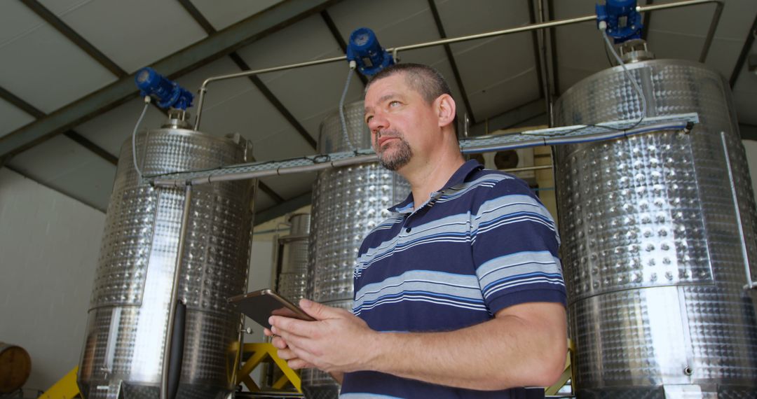 Man Supervising Storage Tanks in Brewery with Tablet - Free Images, Stock Photos and Pictures on Pikwizard.com