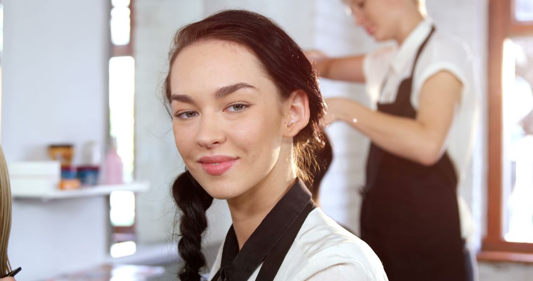 Smiling woman in beauty salon with hair stylist in background - Free Images, Stock Photos and Pictures on Pikwizard.com